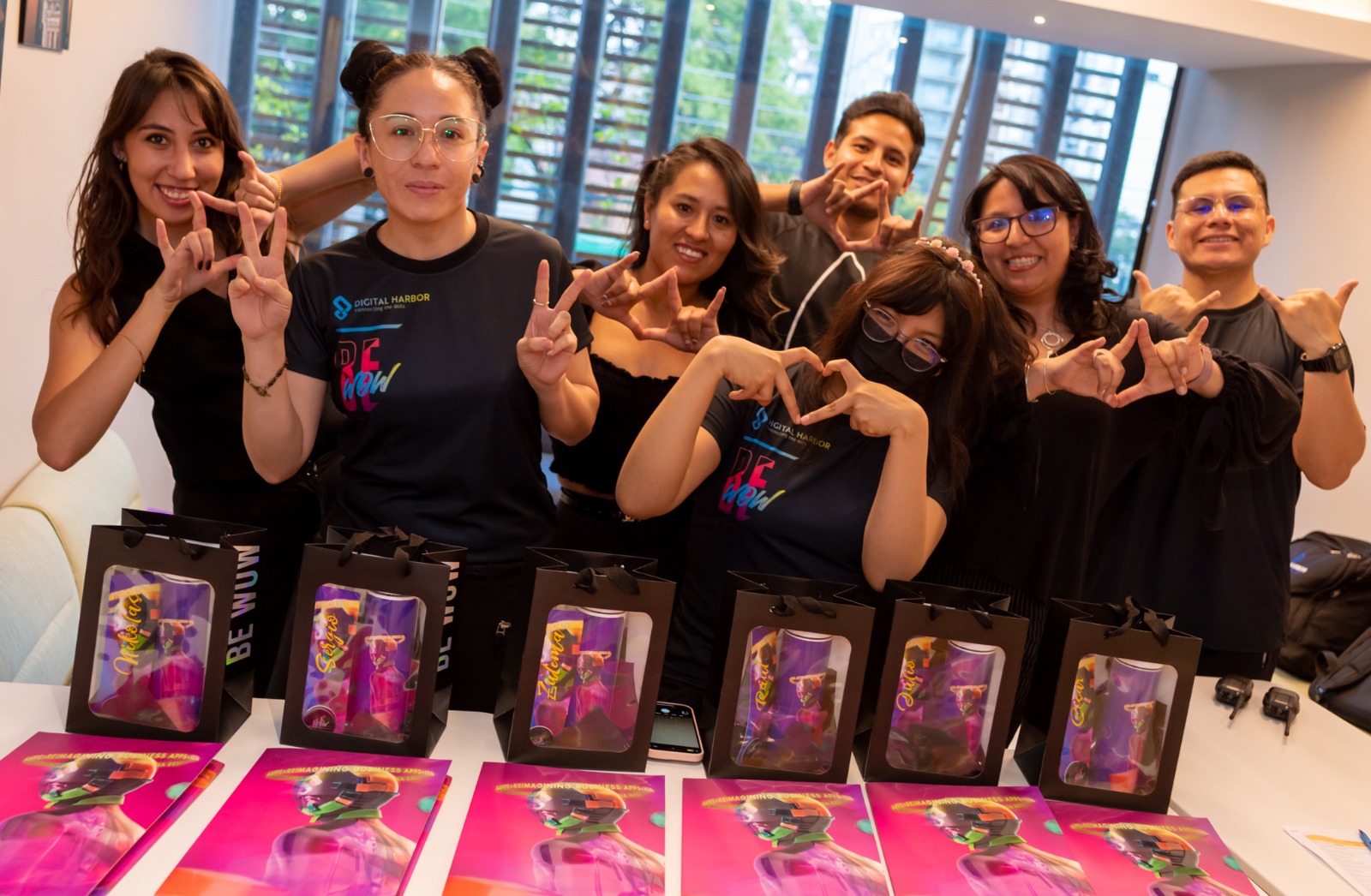 Equipo de marketing de Digital Harbor haciendo gestos con las manos detrás de bolsas de regalo personalizadas
